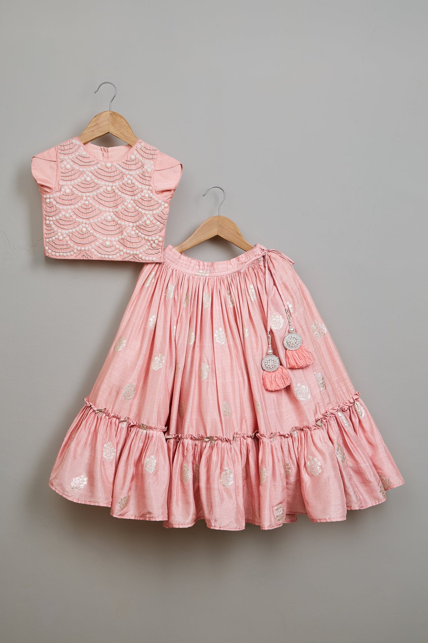 Pink dress and top set on hangers against a gray background

